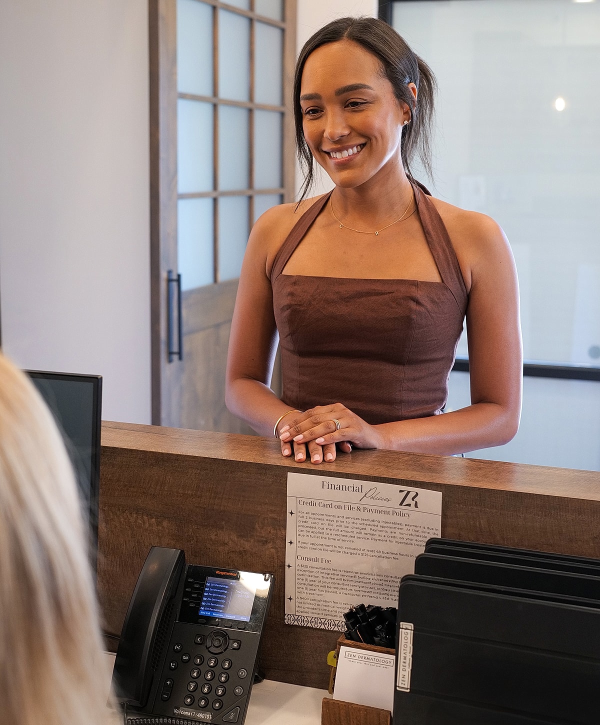 Smiling woman at reception desk in office.