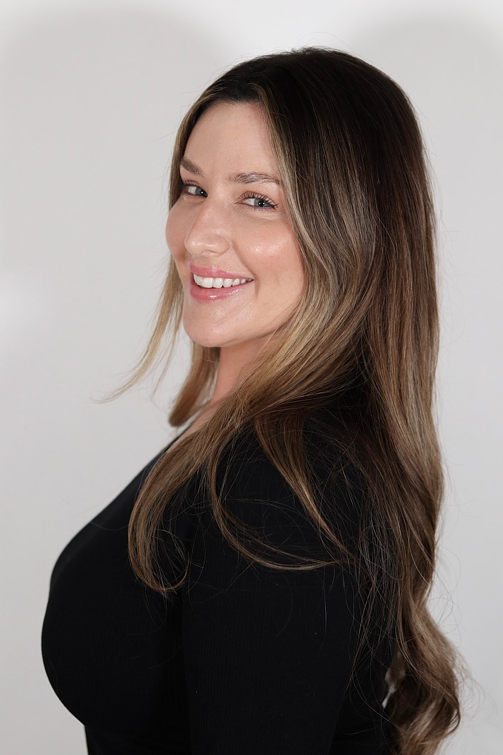 Smiling woman with long hair against white background.