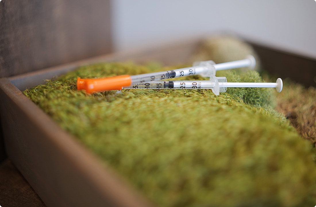 Two syringes on green moss surface.