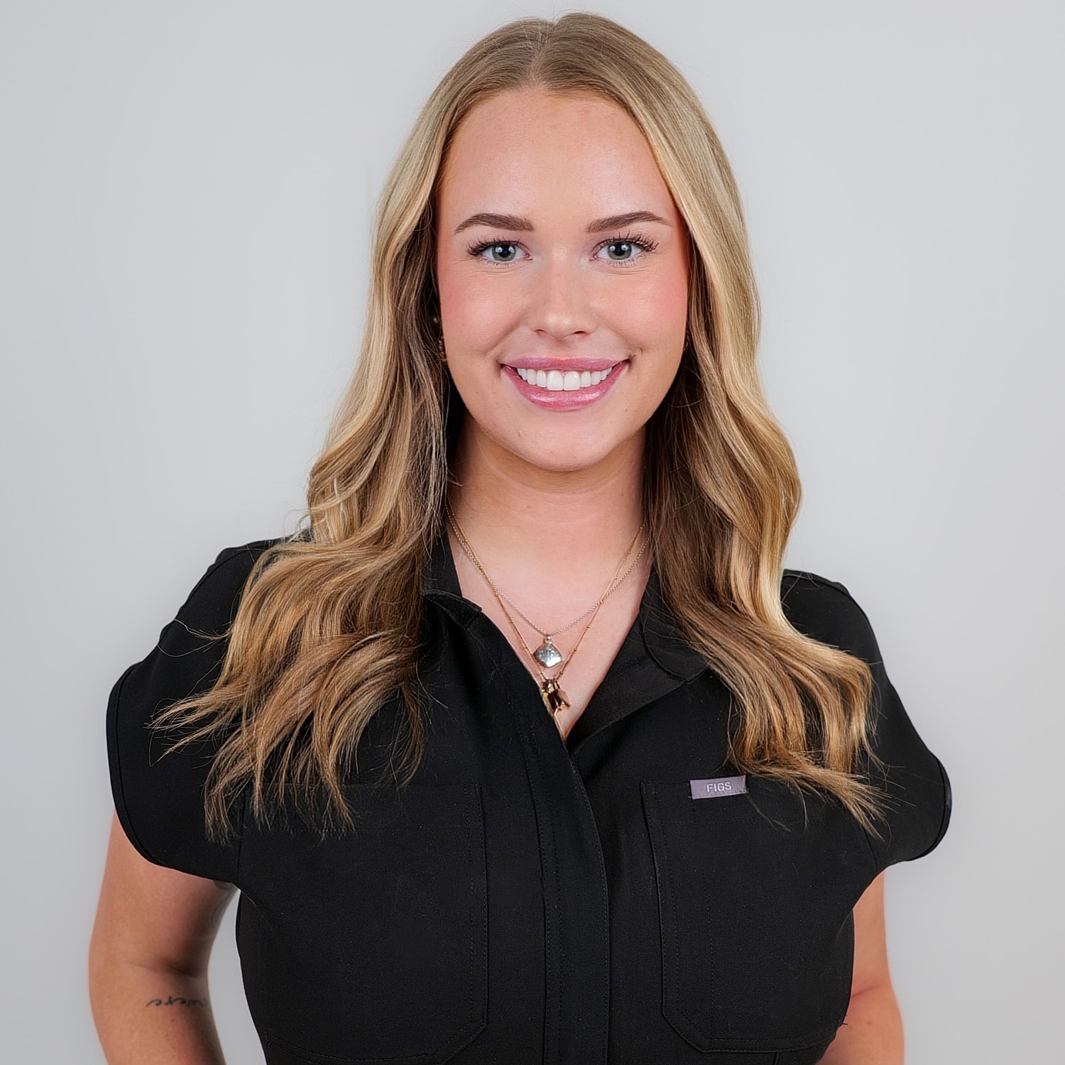 Smiling woman with long hair and necklace.