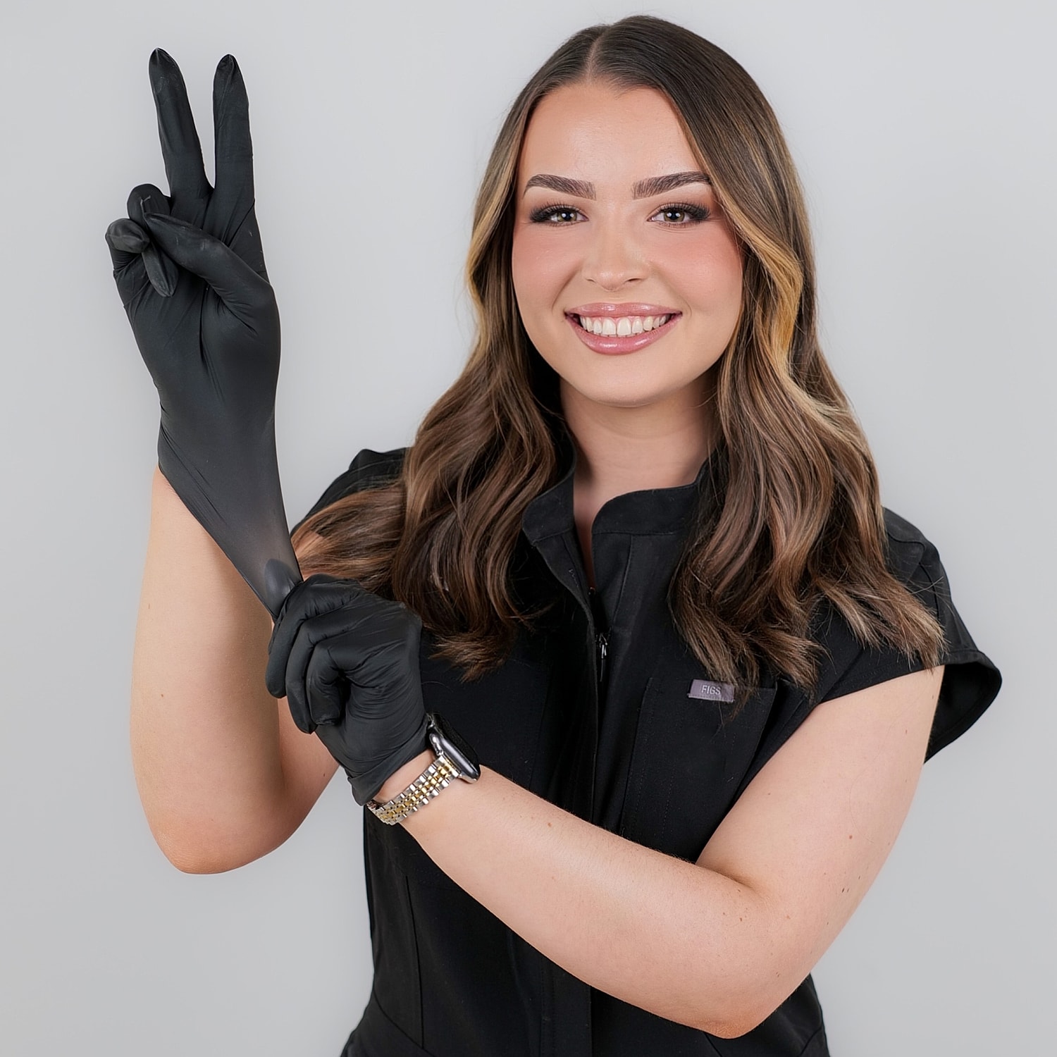 Smiling woman wearing black gloves, making peace sign.