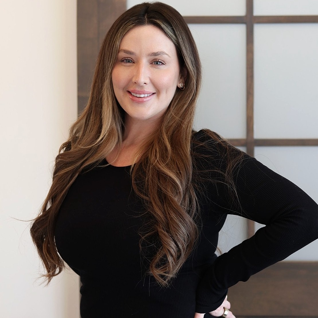 Smiling woman with long hair in black top.