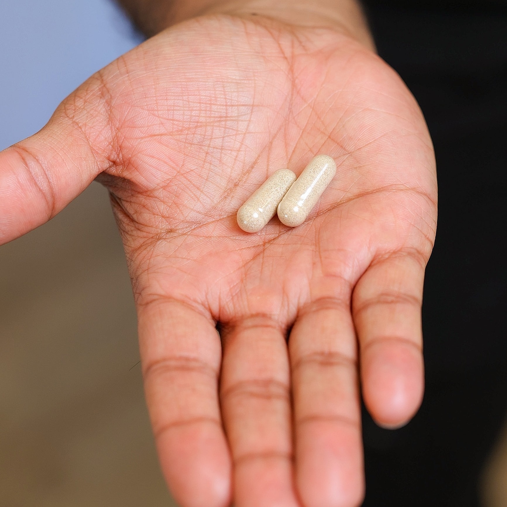 Hand holding two dietary capsules.