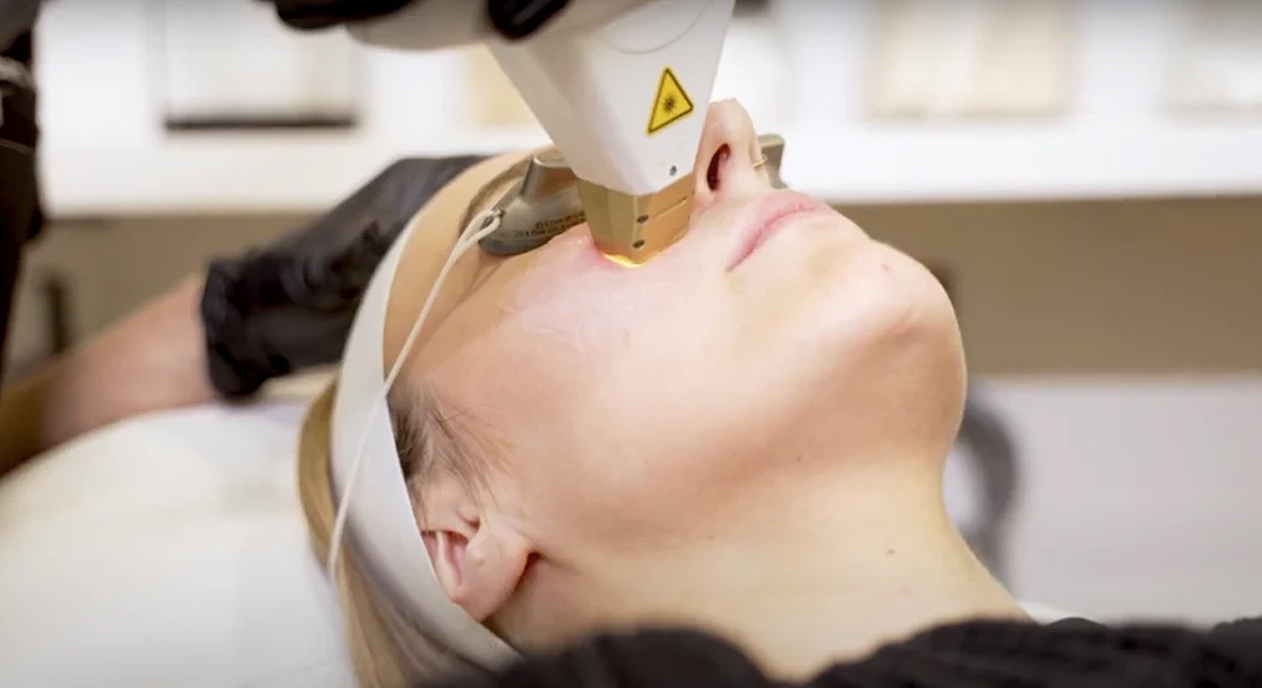 Woman receiving laser facial treatment in spa.