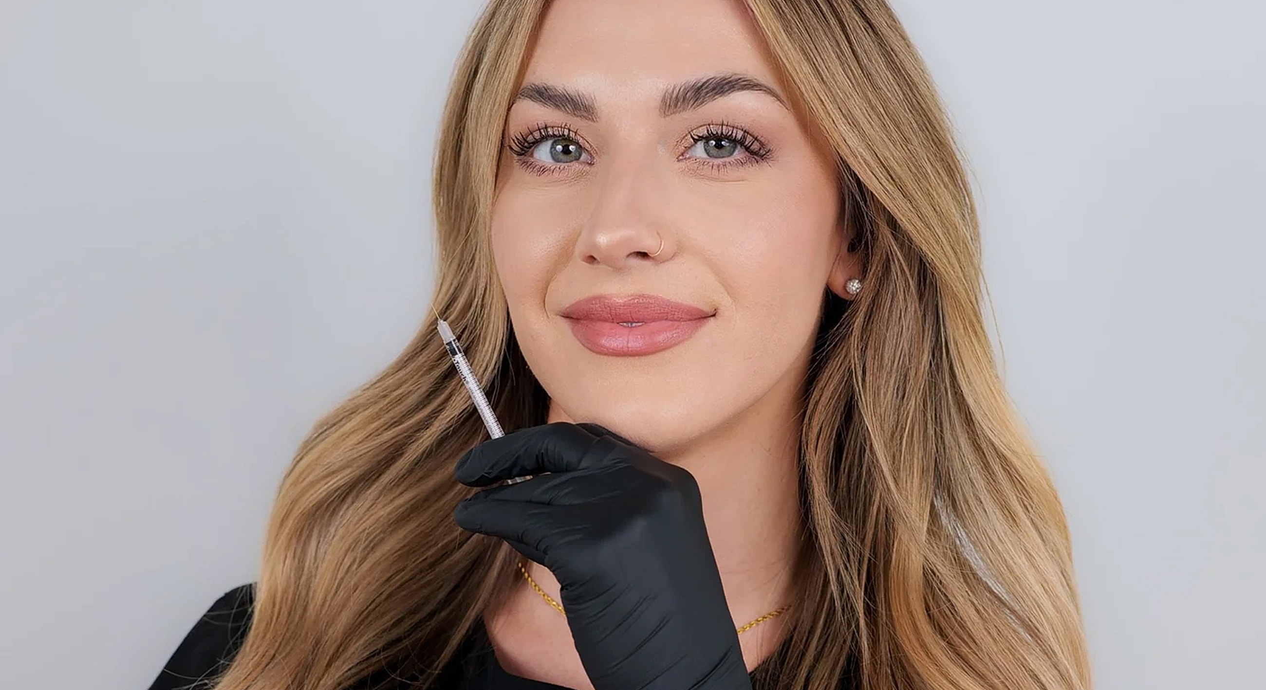 Woman holding syringe, preparing for cosmetic procedure.
