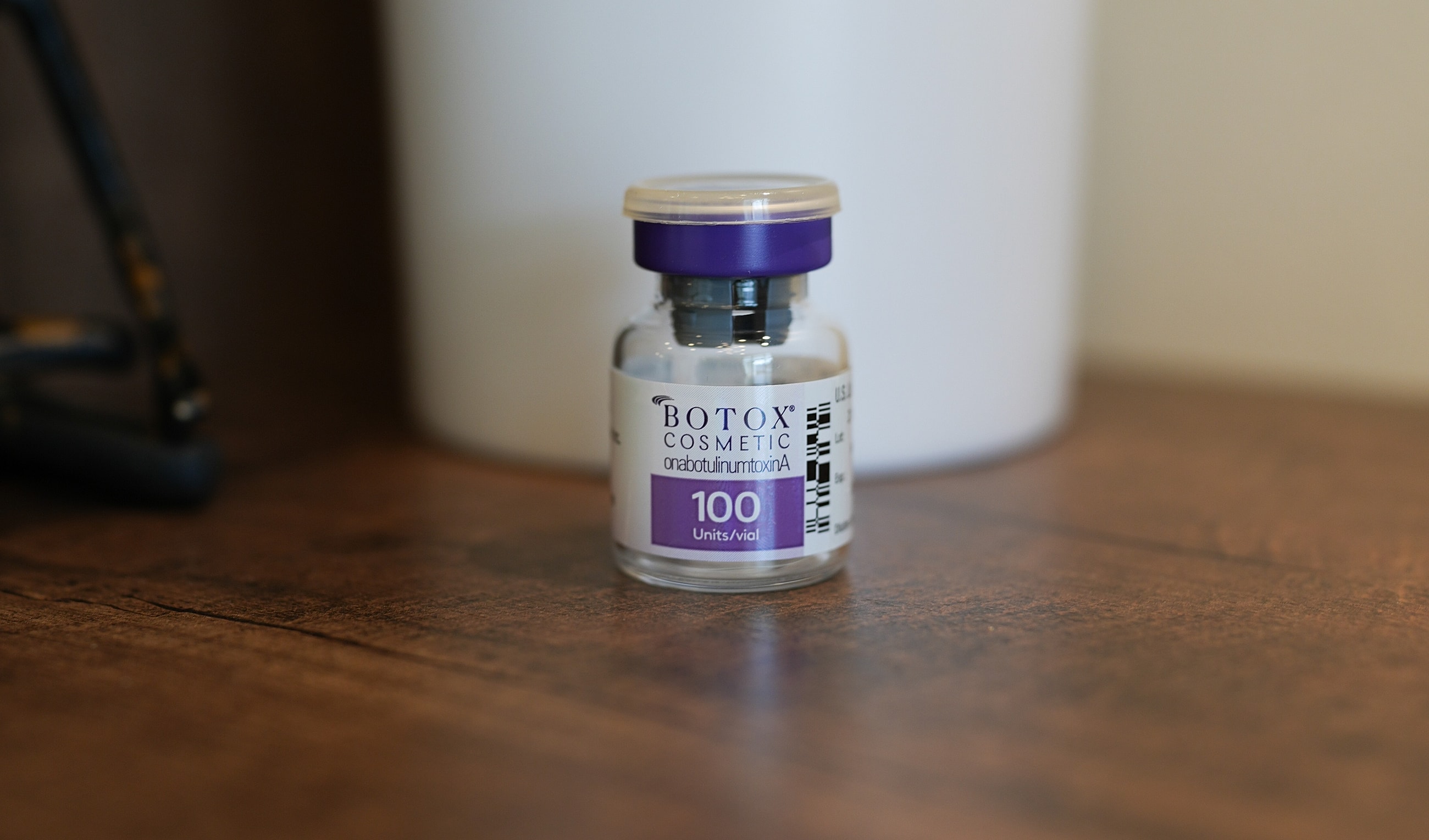Botox cosmetic vial on wooden surface.