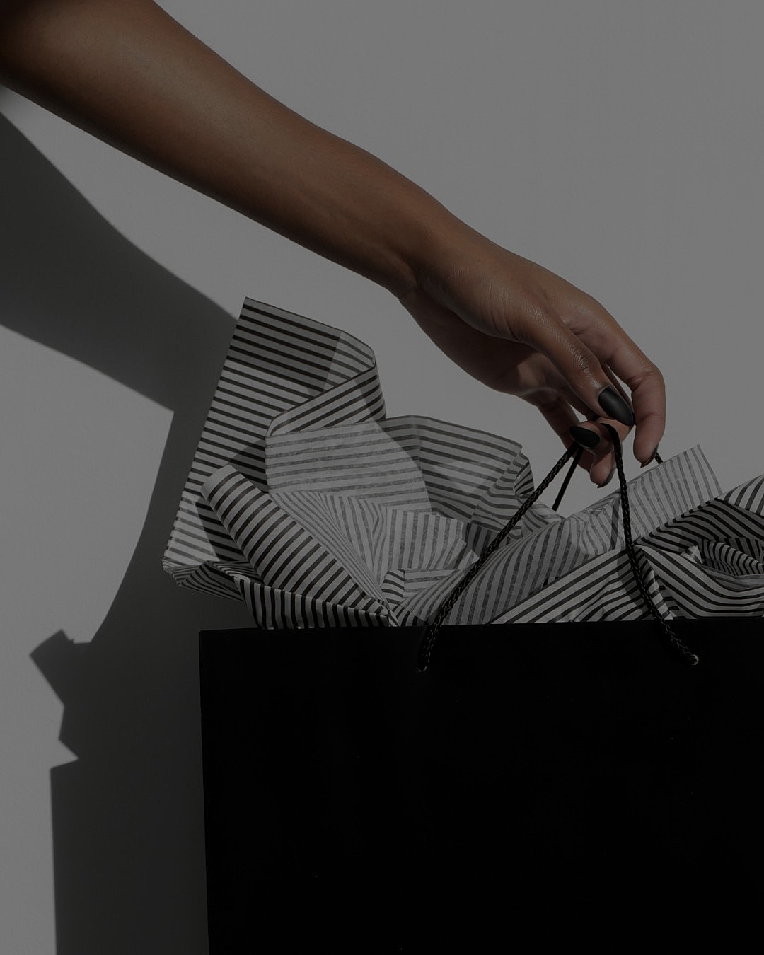 Hand holding a shopping bag with tissue paper.
