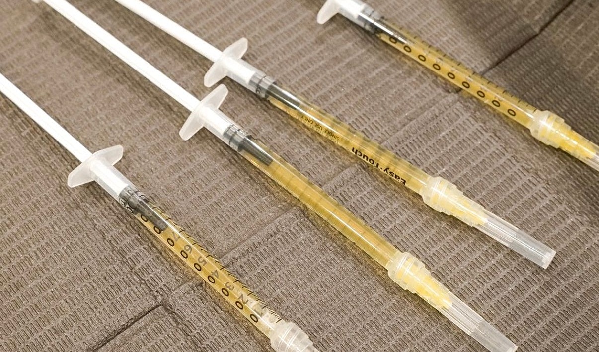 Syringes filled with liquid on a textured surface.